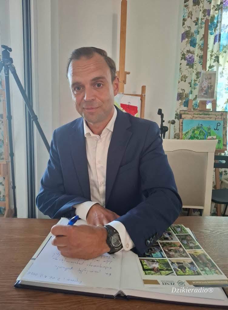dr Tomasz Greniuch wpisuje się do księgi pamiątkowej
